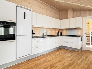 Cozinha moderna com armários brancos, forno embutido e piso de madeira.