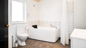 A bathroom with a white toilet, a bathtub, and a shower curtain. - Holiday Home in Hirtshals (Hirtshals)