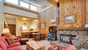 Un salon chaleureux avec une cheminée, des murs en bois et un coin repas.