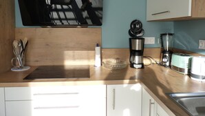 A kitchen with a wooden countertop, a coffee maker, a blender, and a toaster.
