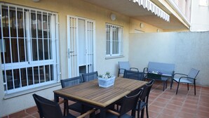 Un patio con una mesa y sillas de madera, una planta pequeña y un banco.