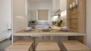 Una cocina moderna con una isla central, armarios blancos y una pared de acento de madera.