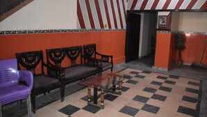 A lobby with a checkered floor, a glass-top table, and a purple chair. - Hotel Royal Lodge (Islamabad)