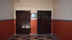 A hallway with two dark wooden doors, a tiled floor, and a small framed picture on the wall. - Hotel Royal Lodge (Islamabad)