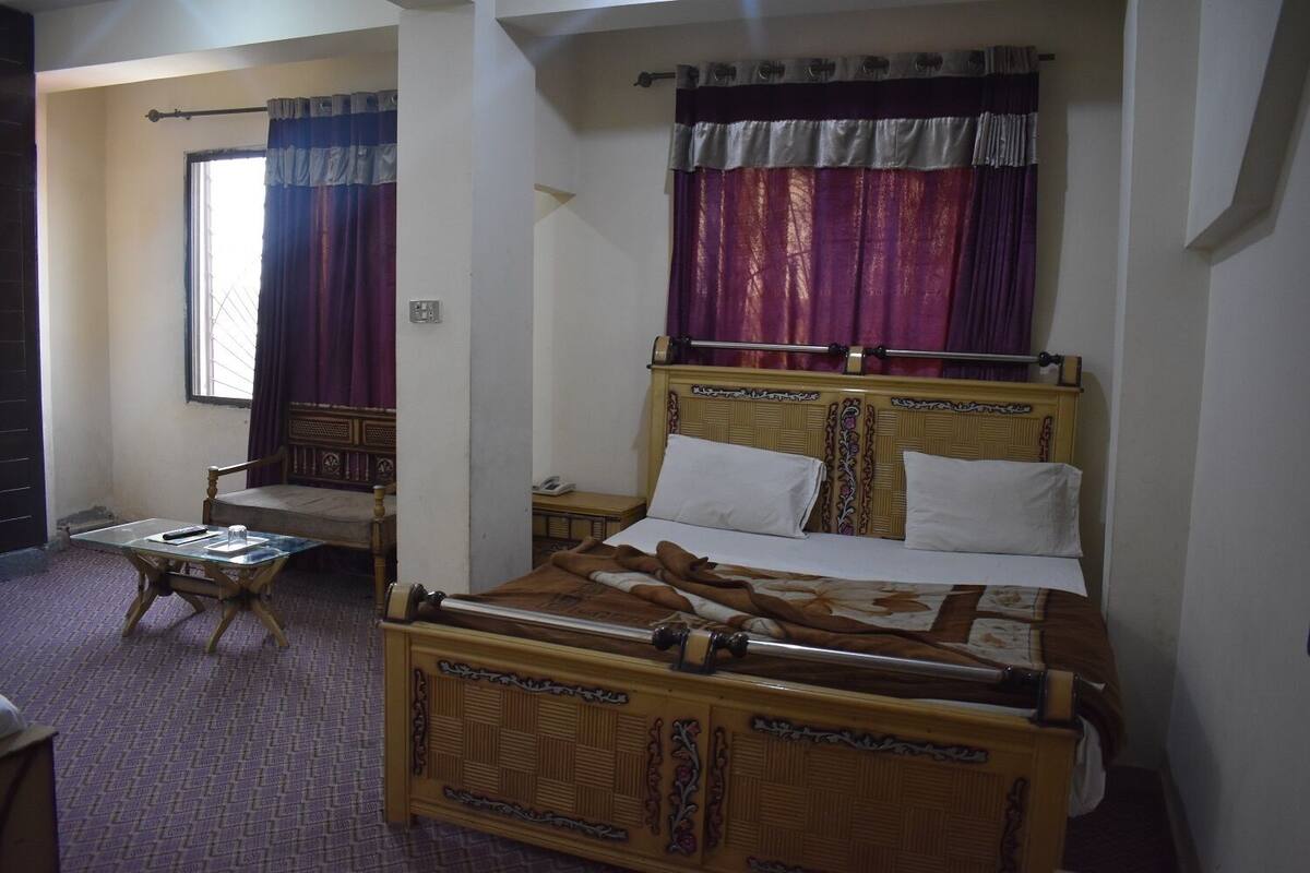 A room with a wooden bed, a small table, and a chair.