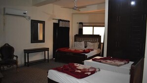 A hotel room with two beds, a chair, a table, a mirror, and a ceiling fan. - Hotel Royal Lodge (Islamabad)