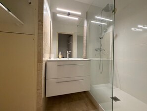 A modern bathroom with a glass-enclosed shower, a white vanity with drawers, and a mirror above the sink. - 2-star apartment with balcony-terrace, 1 bedroom, parking, close to the sea (Les Sables-d'Olonne)
