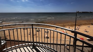 A beach view from a balcony with a railing, sandy beach, and ocean. - 2-star apartment with balcony-terrace, 1 bedroom, parking, close to the sea (Les Sables-d'Olonne)