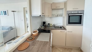 A compact kitchen with a built-in oven, a coffee maker, and a sink. - 2-star apartment with balcony-terrace, 1 bedroom, parking, close to the sea (Les Sables-d'Olonne)