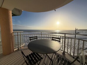 A balcony with a table and chairs, overlooking a beach with waves and a ship in the distance. - 2-star apartment with balcony-terrace, 1 bedroom, parking, close to the sea (Les Sables-d'Olonne)