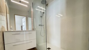 A modern bathroom with a glass-enclosed shower, a white vanity with drawers, and a large mirror. - 2-star apartment with balcony-terrace, 1 bedroom, parking, close to the sea (Les Sables-d'Olonne)