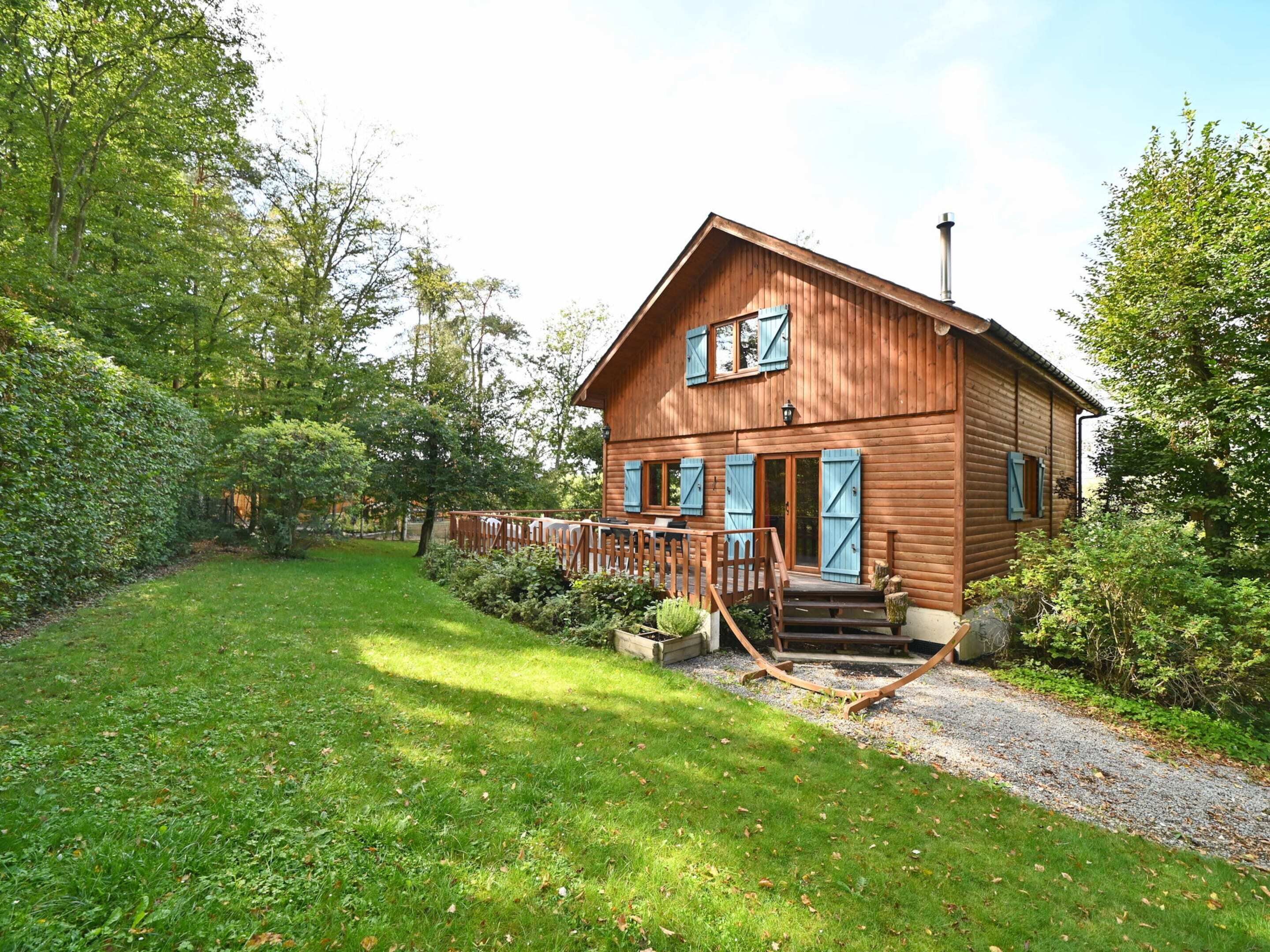 A wooden cabin with a porch, surrounded by lush greenery.