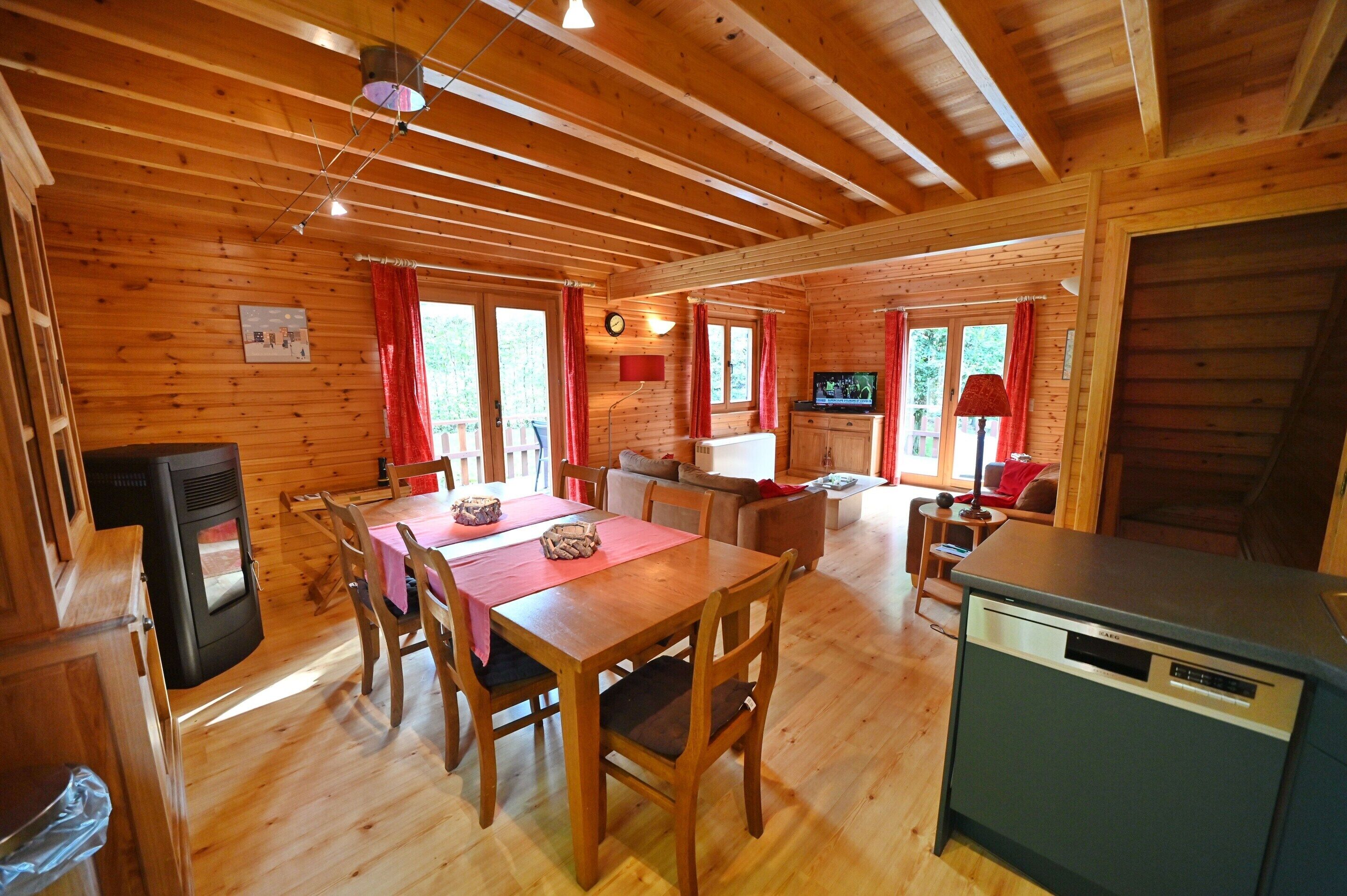 A wooden cabin interior with a dining area, kitchen, and living space.