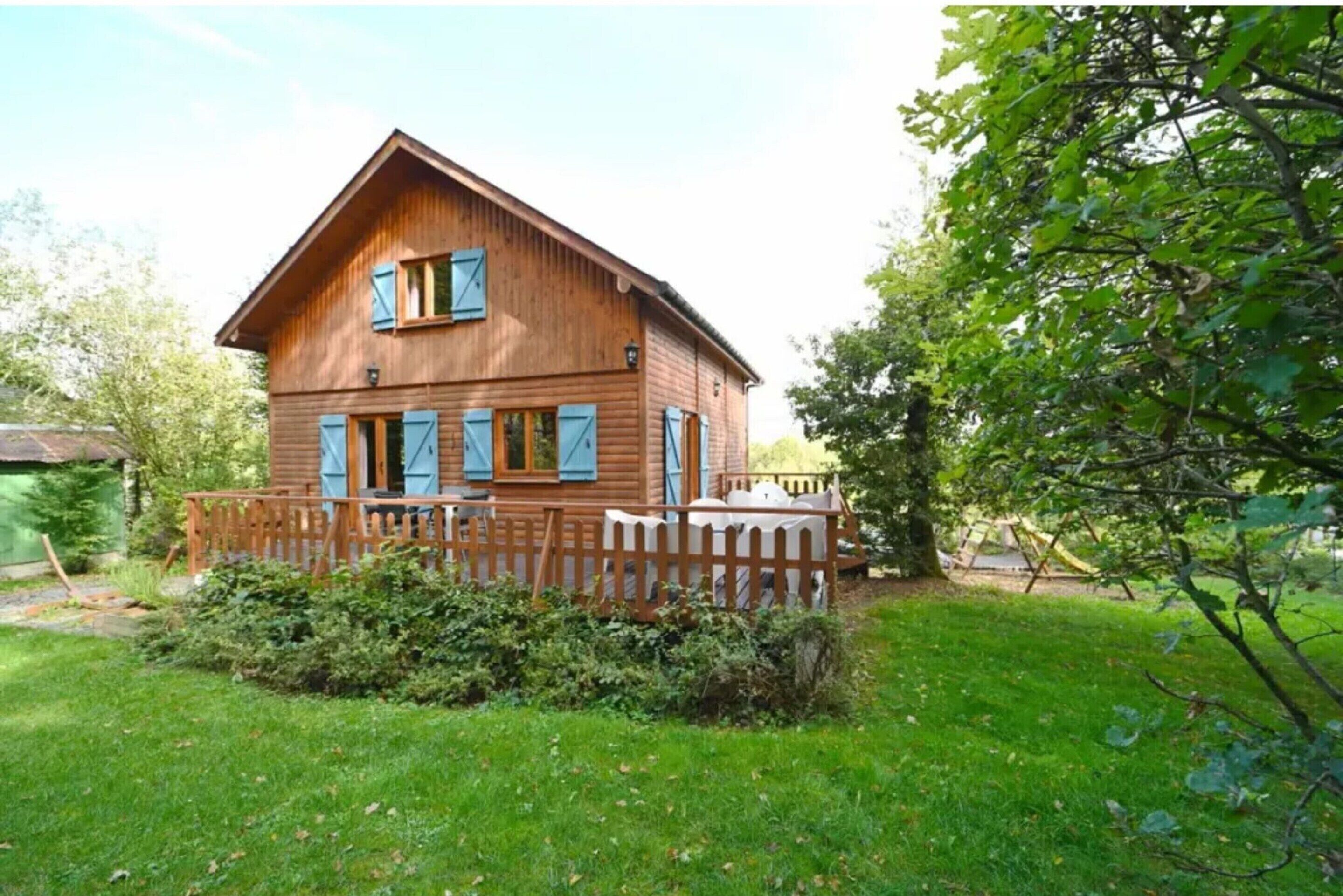 Ein Holshaus mit Veranda, umgeben von einem Holzzaun und viel Grün.