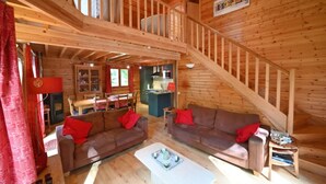 Ein Holzblockhaus mit Schlafzimmer im Zwischengeschoss, Essbereich und Küche.