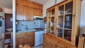 Una cocina compacta con armarios de madera, un lavamanos empotrado y una cafetera.