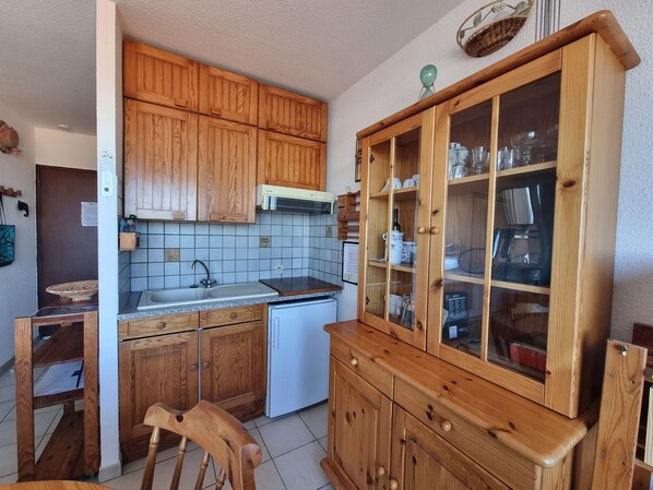 A compact kitchen with wooden cabinets, a built-in sink, and a coffee maker.