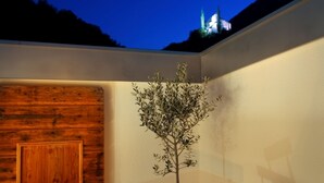 A dining area with a table set for two, a wooden wall, a small tree, and a view of a building in the background. - Above the rooftops of Lana - Blue apartment with terrace and sauna - viaDolceVita (Lana)