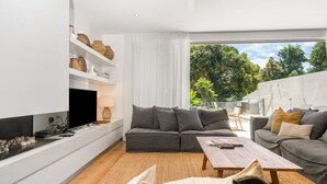 A modern living room with a grey sofa, a wooden coffee table, and a flat-screen TV.
