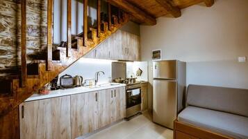 A kitchen with wooden cabinets, a built-in oven, a refrigerator, and a wooden staircase.