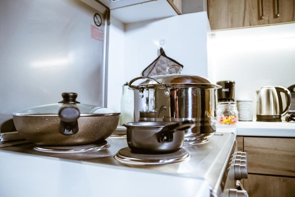A kitchen with a stove, pots, and a kettle.