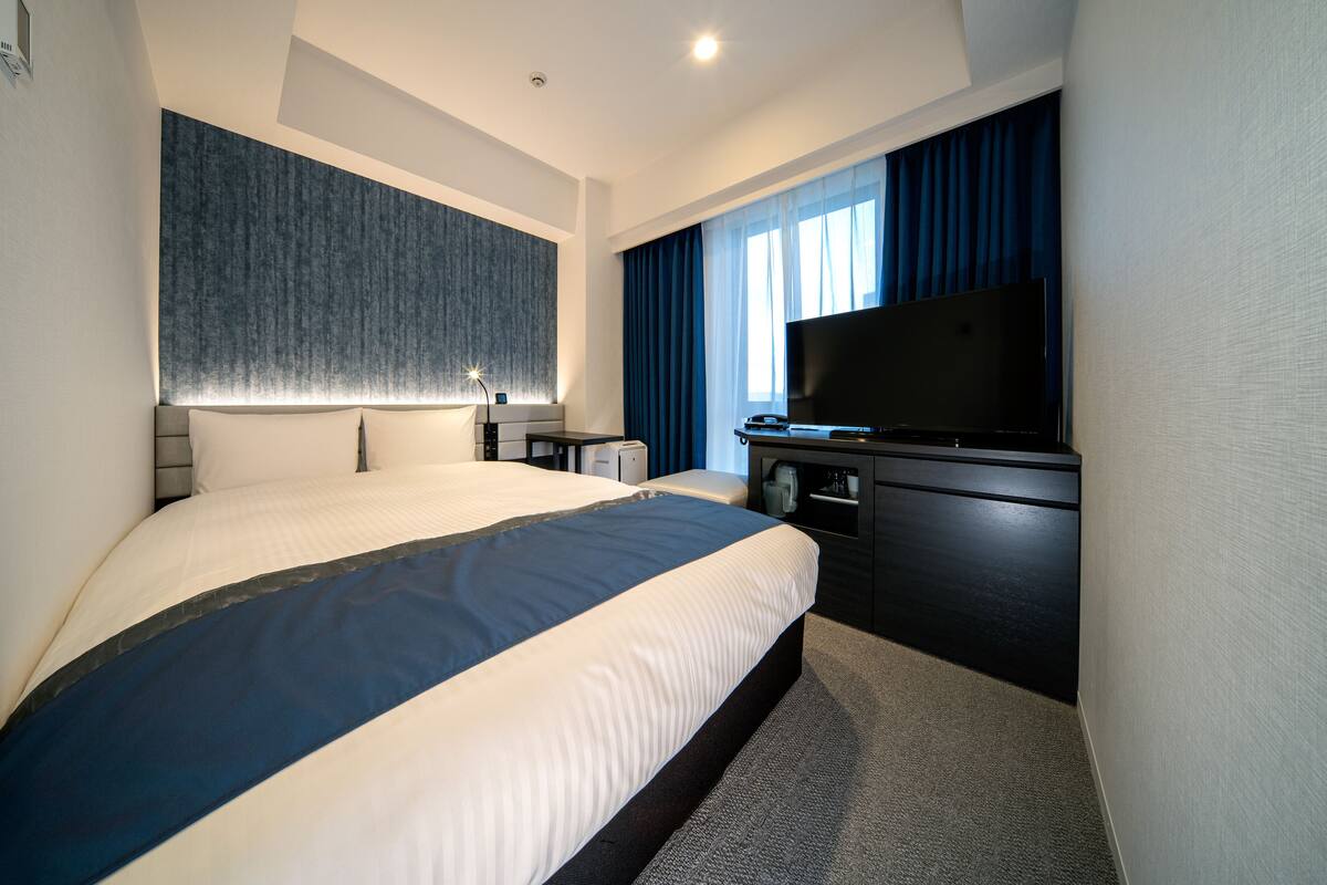 Een moderne hotelkamer met een groot bed, een flatscreen televisie, een bureau en een kledingkast.
