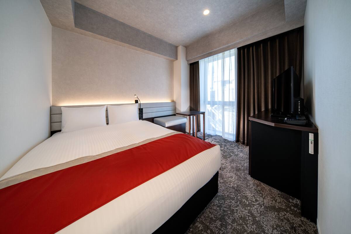 Een moderne hotelkamer met een groot bed, een bureau en een televisie.