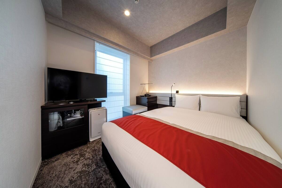 Een hotelkamer met een bed, een televisie, een bureau en een raam.