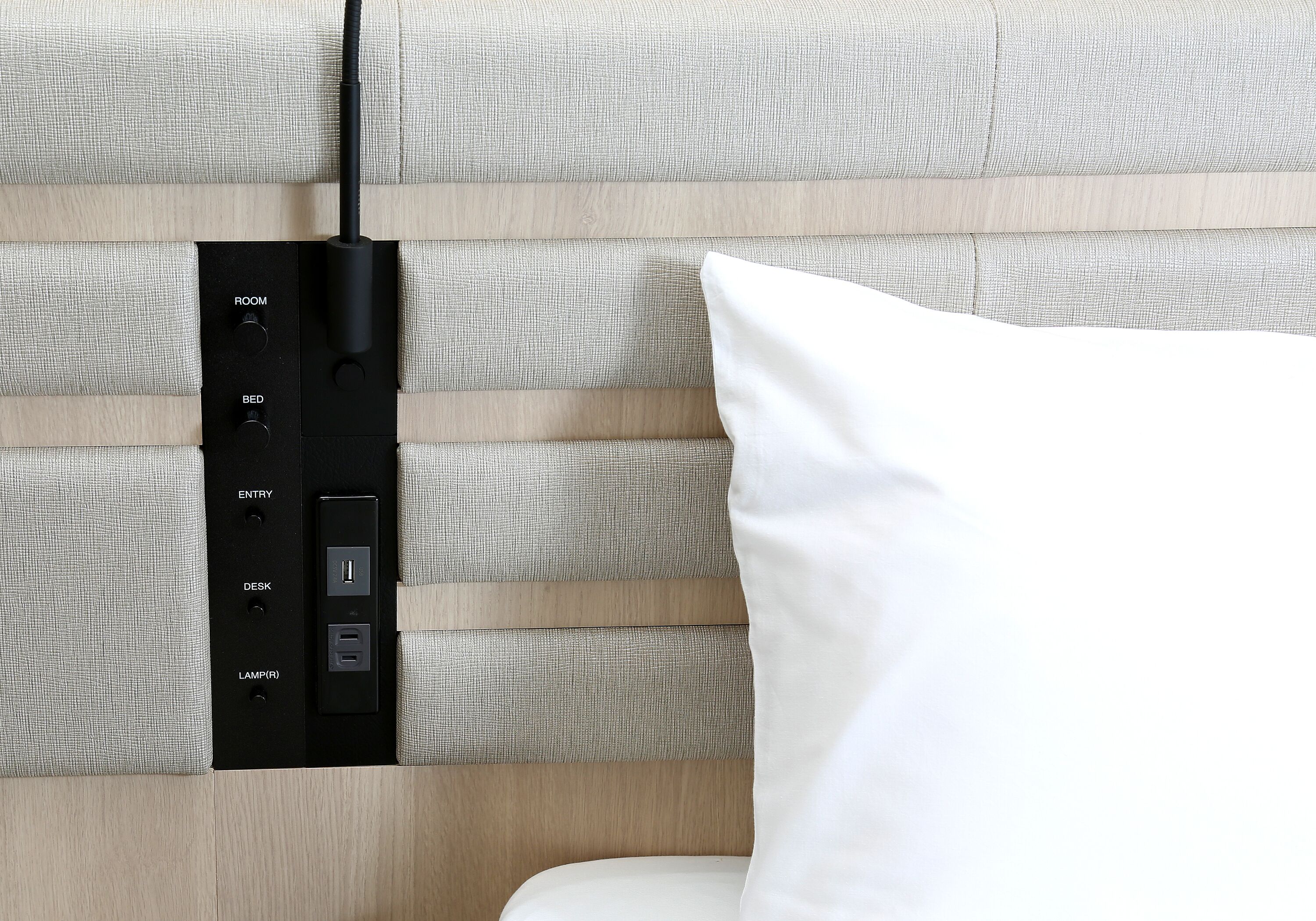Un panneau de commande mural doté de boutons étiquetés pour les fonctions suivantes : PIÈCE, LIT, ENTRÉE, BUREAU et LAMPE (R).