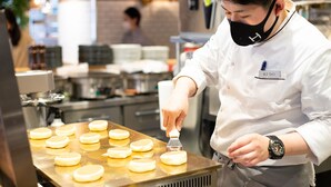 A chef in a white uniform with a name tag, preparing food on a counter. - DEL style Ikebukuro Higashiguchi by Daiwa Roynet Hotel (Tokyo)