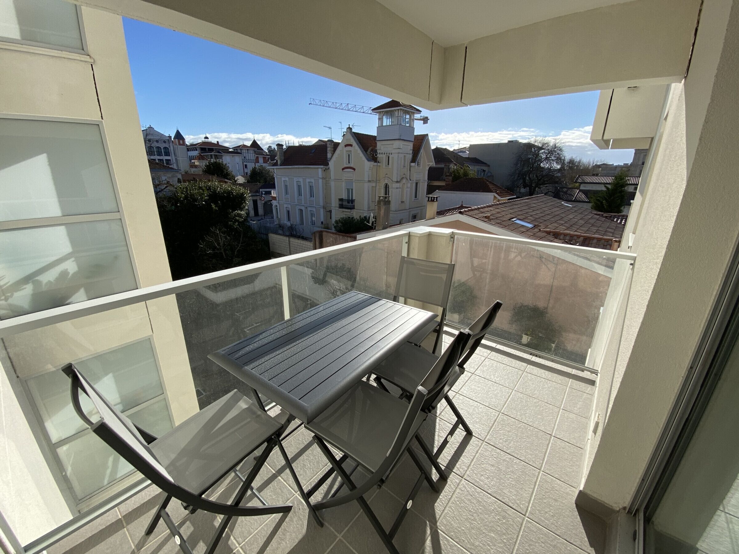 A balcony with a table and chairs, offering a view of buildings and a tower in the background.