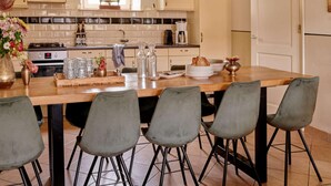 A kitchen with a central island, bar stools, pendant lights, and a tiled backsplash. - Holiday Home in Baarlo With Hot Tub (Baarlo)