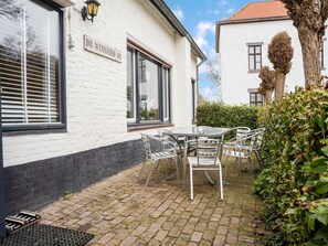 A white building with a sign reading 'DE WINGERD 40,' a paved patio with a table and chairs, and a hedge in the foreground. - Chalet in Ulestraten Near Maastricht (Ulestraten)