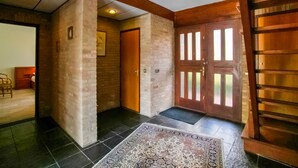 A hallway with a wooden door, a patterned rug, and a staircase.