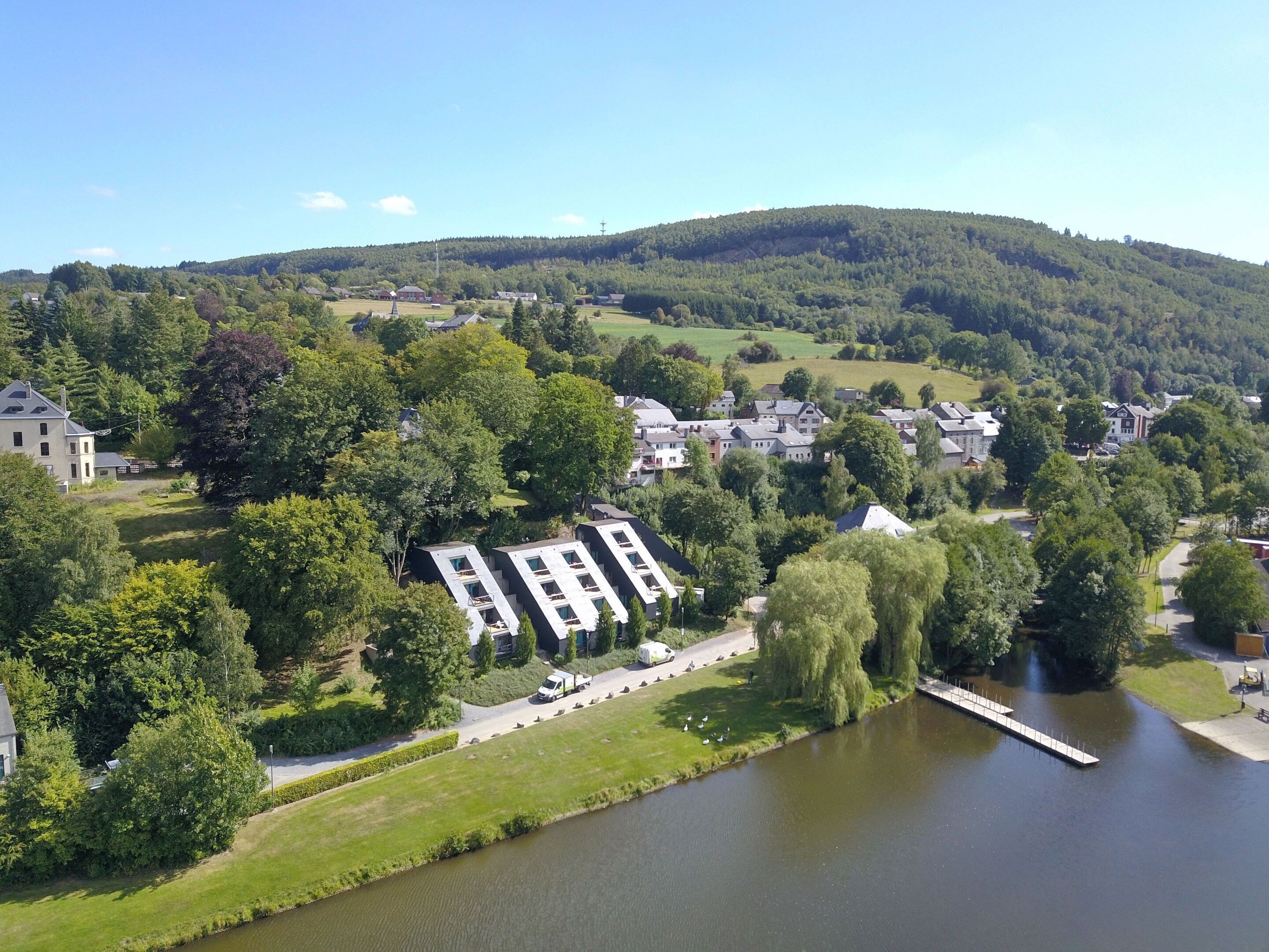 A residential area with a river, houses, and a hill in the background.