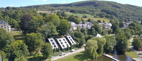 A residential area with a river, houses, and a hill in the background.
