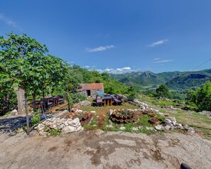 Een rustiek stenen gebouw met een rode dakbedekking, omringd door een wijngaard en een rotsachtig landschap.