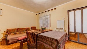 Un accogliente soggiorno con pavimento in legno, un divano, un tavolo con tovaglia a quadri e un piano cottura bianco.