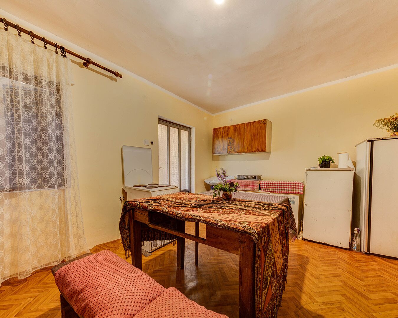 Una cocina compacta con una mesa de comedor, una banca, un refrigerador y una estufa.