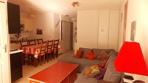 A compact living space with a dining area, sofa, and a red lamp. - Charming 2-Room with Garden, Near Luchon, Sleeps 6, Pets Welcome, Private Parking (Montauban-de-Luchon)