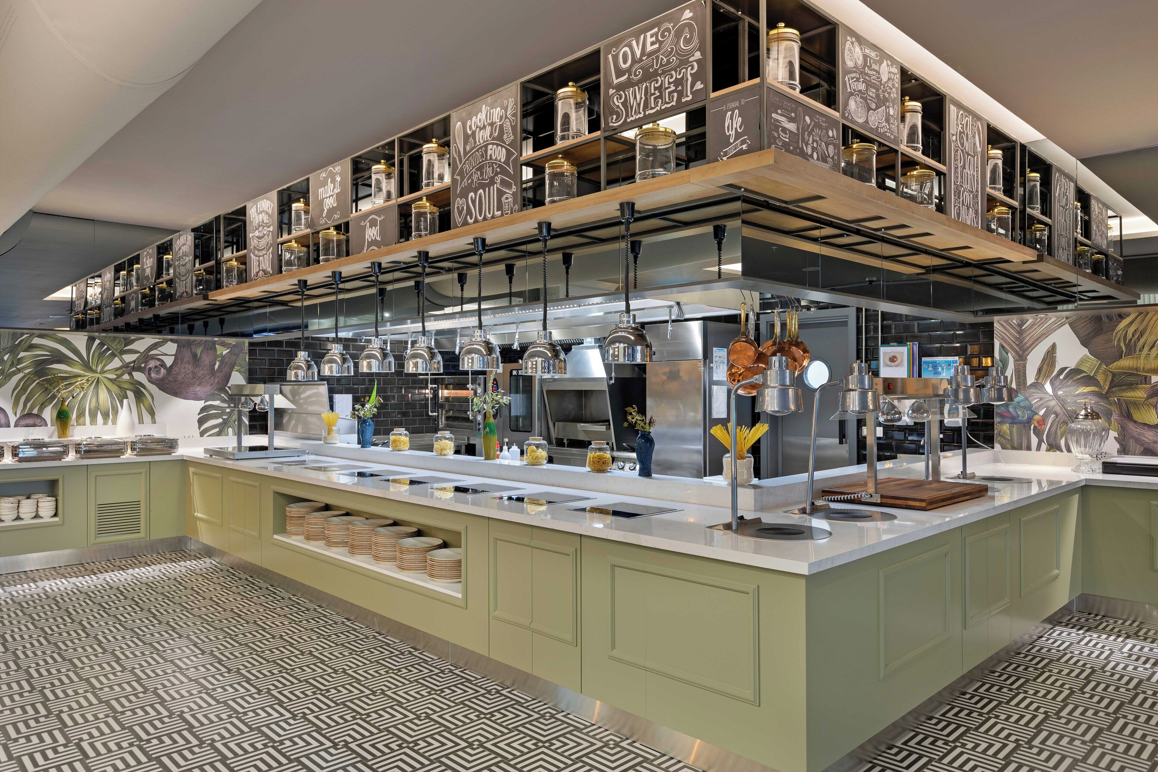 Uma cozinha moderna com uma ilha central, eletrodomésticos de aço inoxidável e potes decorativos nas prateleiras.