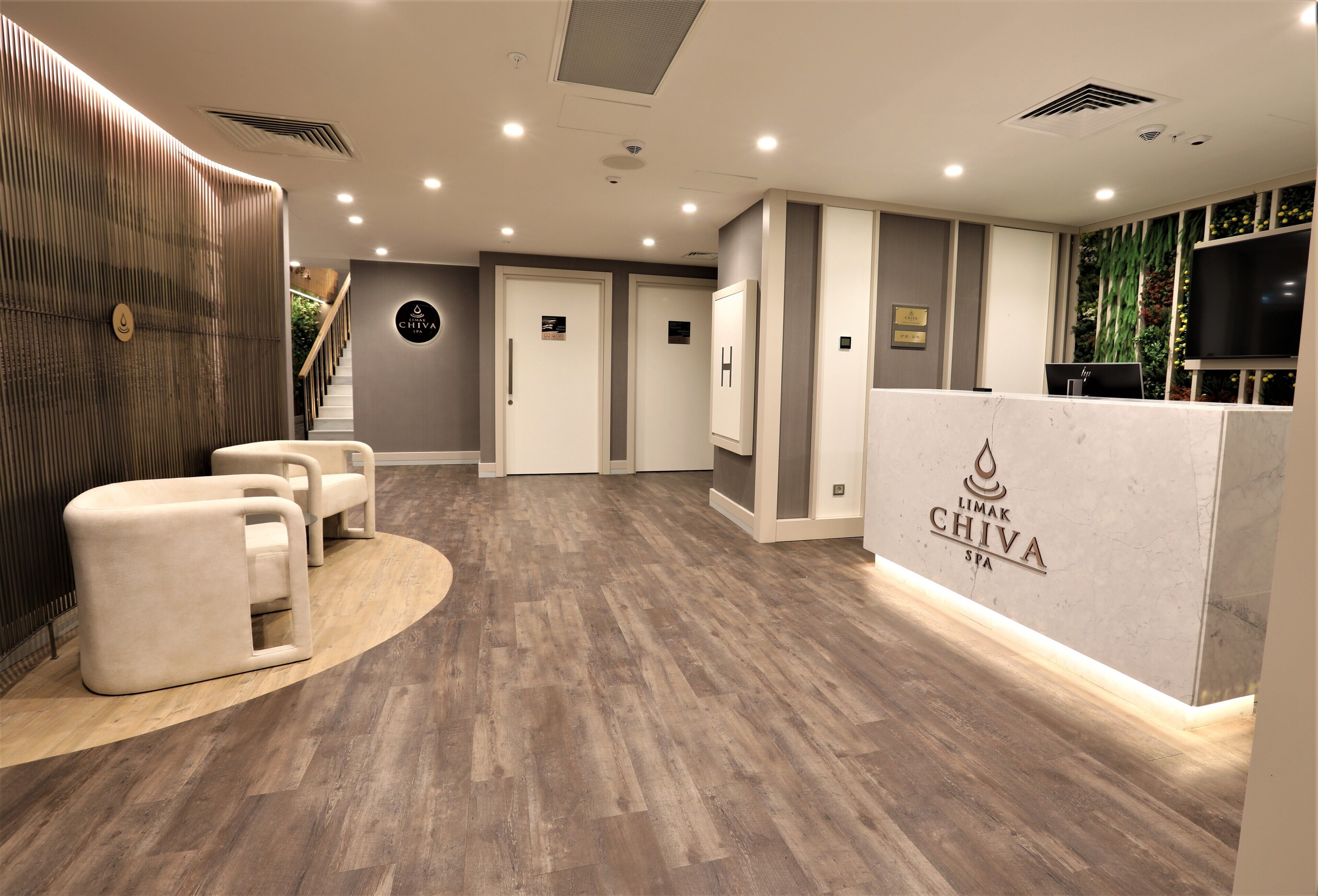 A reception area with a modern design, featuring a reception desk, seating area, and a wall-mounted TV.