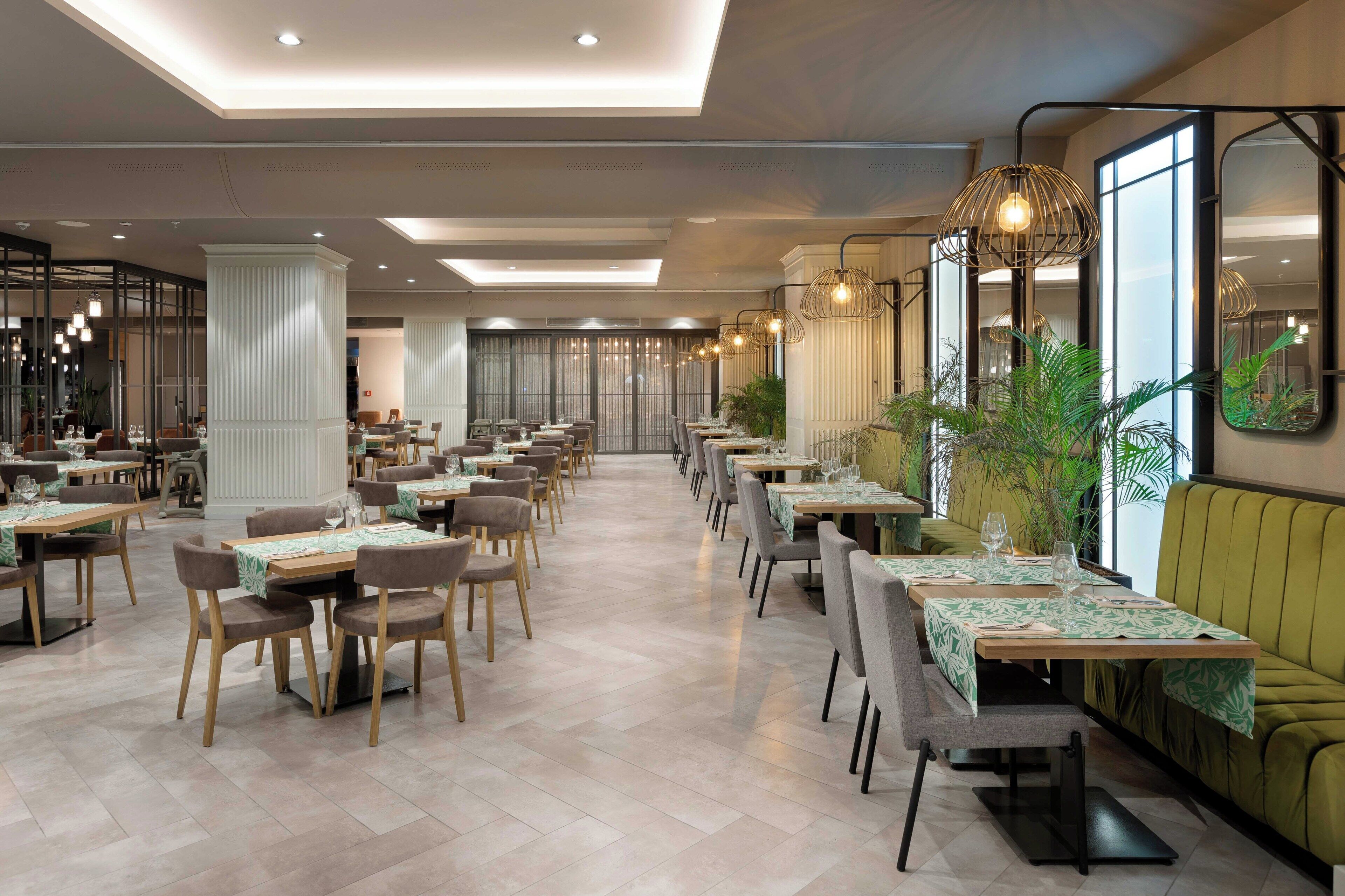 A spacious restaurant with multiple dining tables, chairs, and a seating area with a sofa.