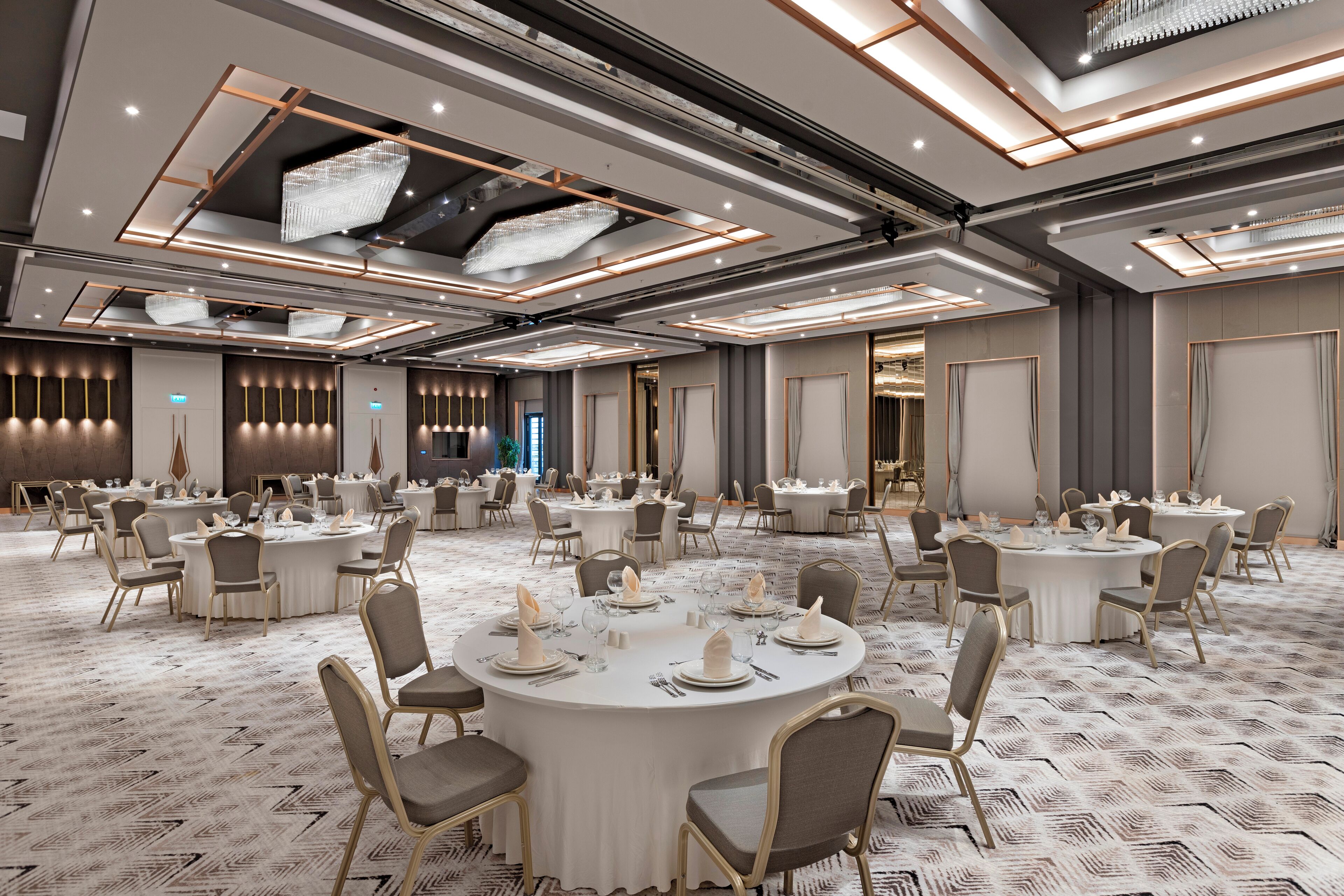 A spacious conference room with round tables, chairs, and a patterned carpet.