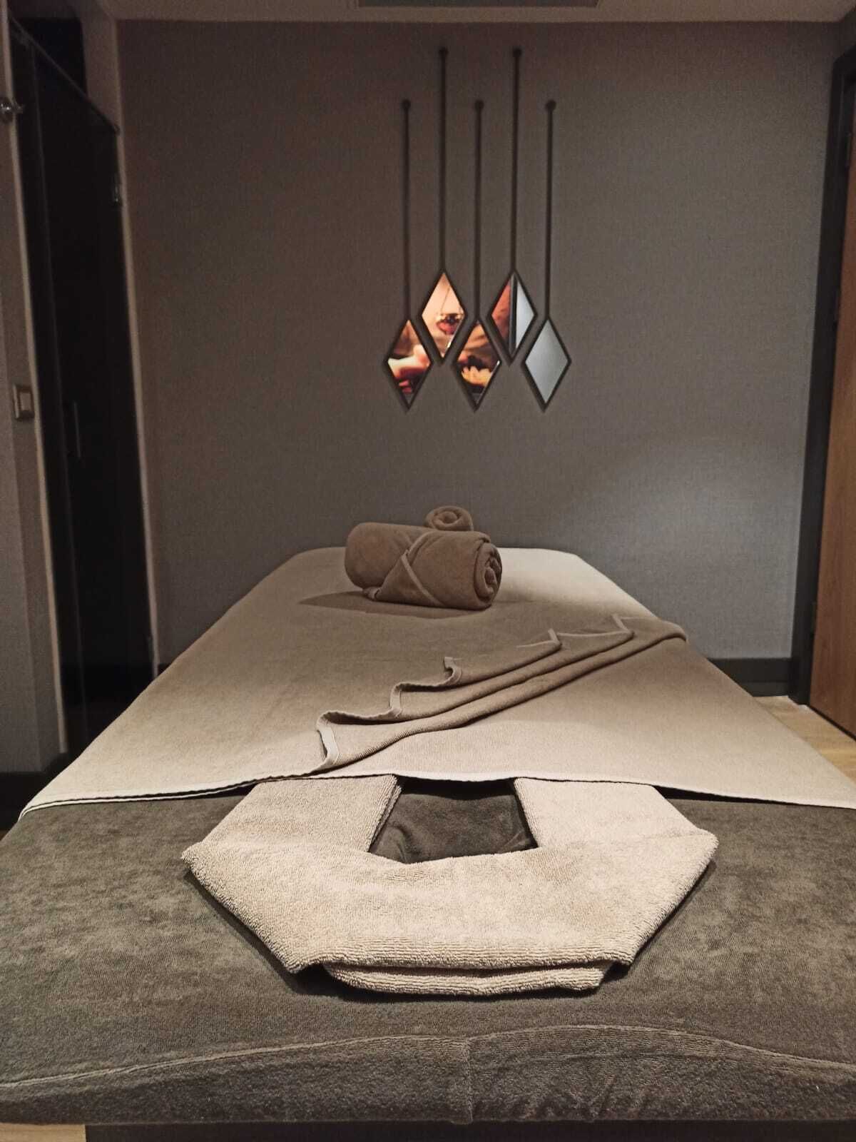 A massage table with towels and a wall-mounted light fixture.