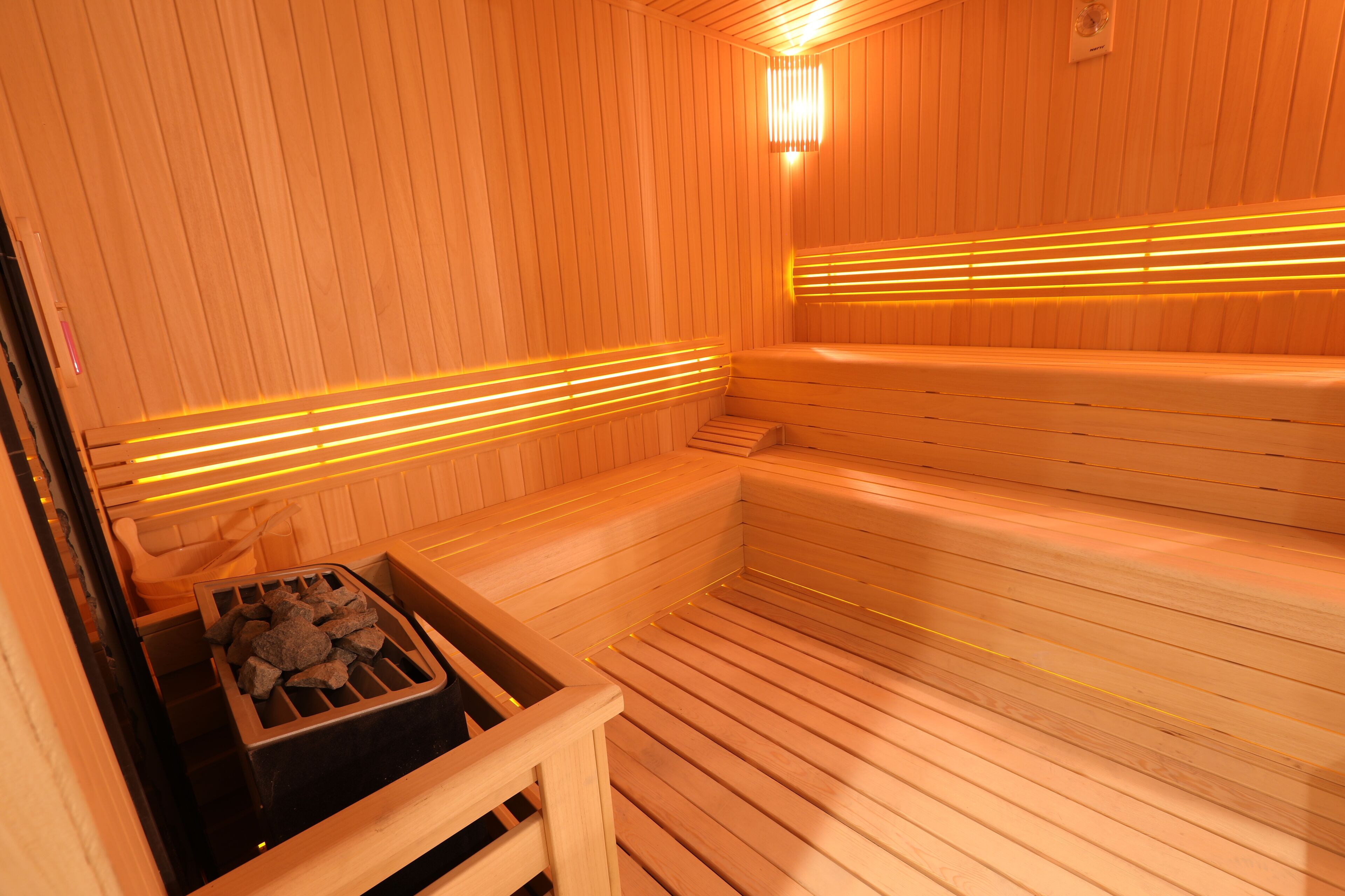 A sauna with wooden benches and a stone heating element.