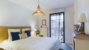 Habitación de hotel con una cama grande, una mesita de noche con lámpara, una silla y vistas al exterior a través de una ventana.