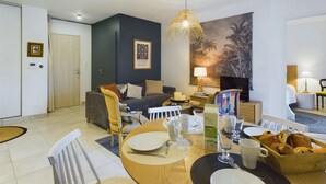 Una sala de estar moderna con un sofá, una mesa de comedor y un cuadro grande en la pared.