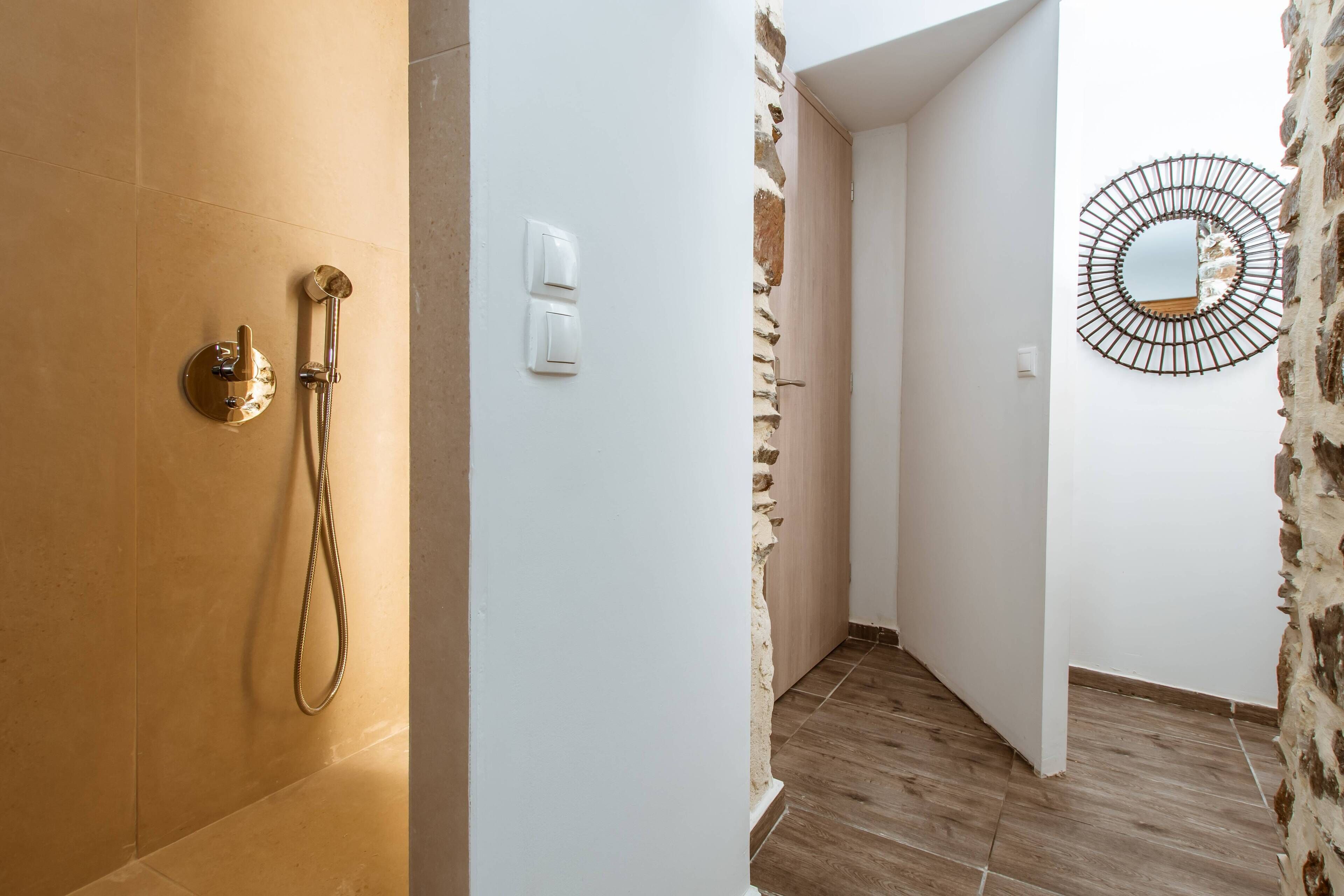 Un baño con ducha, pared blanca y espejo.