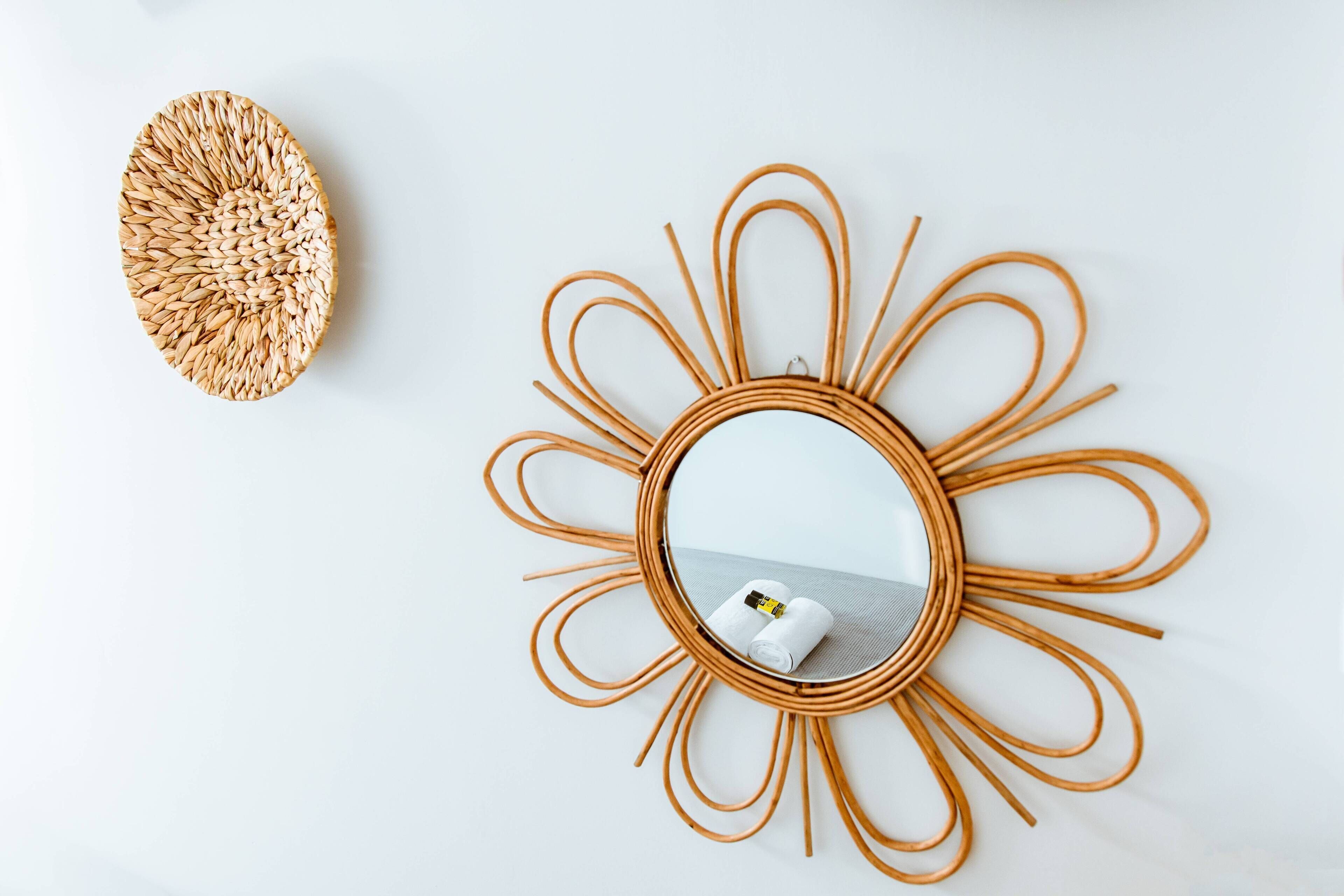 Un miroir rond avec un cadre évoquant un soleil et une décoration murale tissée.